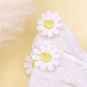 Vue détaillée de la pince à cheveux en dentelle blanche avec broderies de marguerites