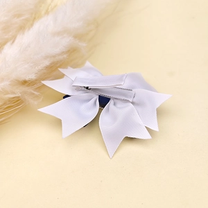 Detail of multi-layered white grosgrain ribbon hair bow with metal alligator clip back