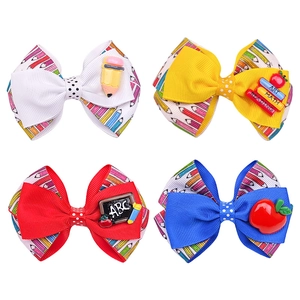 Détail de barrettes nœuds scolaires avec motifs crayons et icônes de papeterie en résine