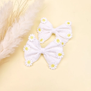 Détail de deux barrettes à cheveux en dentelle faites à la main avec de petites marguerites