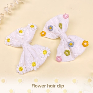 Détail de barrettes nœuds en dentelle blanche avec broderie de marguerites pour filles