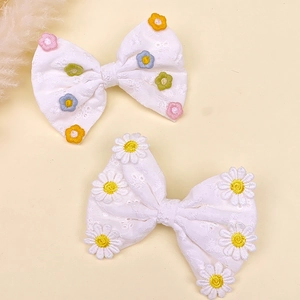 Détail de barrettes nœuds brodés blancs avec motifs marguerites colorés pour les filles