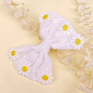 Détail d'une barrette en dentelle faite main avec nœud blanc et broderie fleurie marguerite