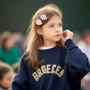 Close-up of a child wearing white baseball themed hair clips with red stitched patterns