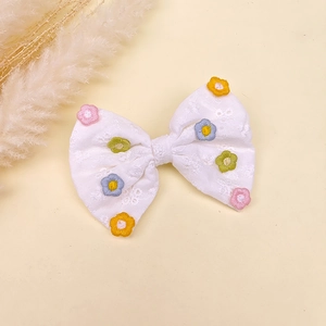 Détail d'un nœud papillon en dentelle blanche avec broderies de marguerites