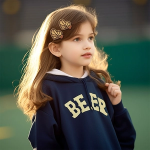 Detailed view of a young girl wearing heart-shaped gold sequin football hair clips outdoors