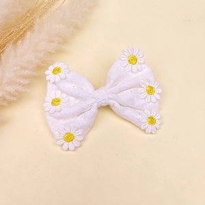 Détail de la barrette à nœud en dentelle blanche faite main avec broderie de marguerites