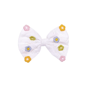 Détail d'un nœud papillon blanc en tissu fait main avec broderies de marguerites colorées