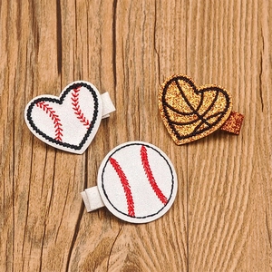 Detail view of football and baseball themed glitter hair clips on a wood background