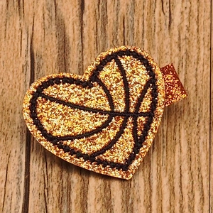 Detail of glitter basketball heart hair clip with embroidery on wood background