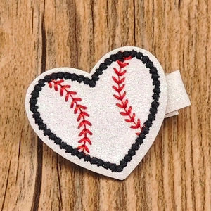 Detailed view of a heart-shaped glitter baseball hair clip with red embroidery threads