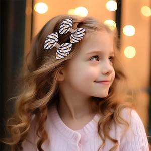 Dettaglio delle mollette a righe con cuori dorati sui capelli di una bambina piccola