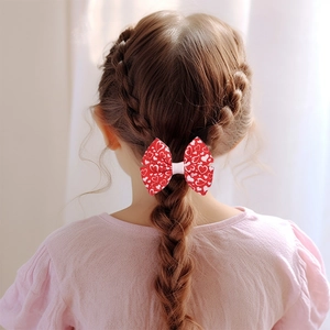 Dettaglio di un fiocco rosso con cuori bianchi su un'acconciatura di bambina