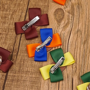 Nahaufnahme bunter Grosgrain-Haarschleifen mit silbernen Metallclips auf Holzgrund