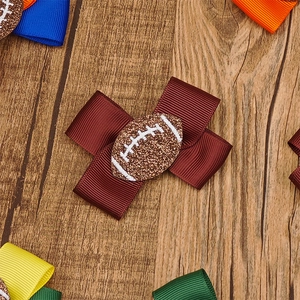 Detail einer burgunderroten Schleifen-Haarklammer mit glitzerndem American Football