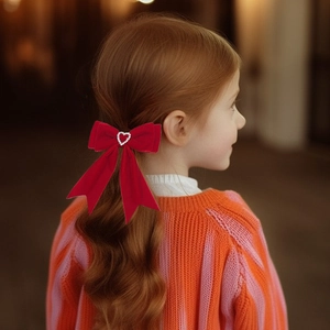 Détail d'un nœud en velours rouge avec strass en forme de cœur sur les cheveux
