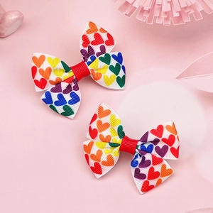 Dettaglio di due fiocchi per capelli in nastro grosgrain bianco con cuori arcobaleno