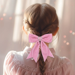 Vue détaillée d'un nœud en velours rose avec strass en cœur sur les cheveux d'une fille