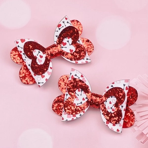 Vue détaillée de deux pinces à cheveux à nœud avec paillettes rouges et motifs de cœurs