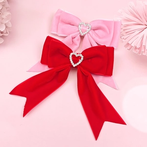 Détail de barrettes à nœuds en velours rouge et rose avec strass en forme de cœur
