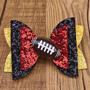 Détail d'une pince à cheveux à paillettes avec un motif football sur fond de bois