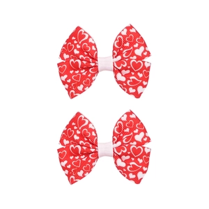 Dettaglio di due fiocchi rossi con motivi a cuore bianco su nastro in gros-grain a coste