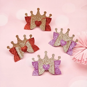 Detail of glitter crown hair clips with festive red bows and shimmering gold accents