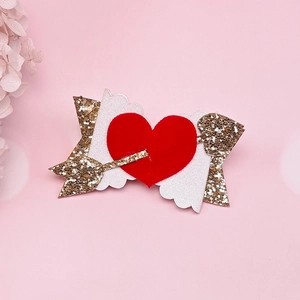 Vista dettagliata di un fiocco per capelli a cuore rosso floccato con freccia dorata glitter
