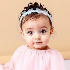 Detailed view of soft white lace baby headband featuring delicate embroidered butterfly patterns