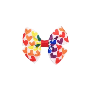 Dettaglio di un mini fiocco per capelli con stampa a cuore arcobaleno su nastro