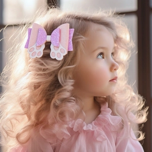 Girl wearing a pink and purple glitter bow hair clip with a white paw motif