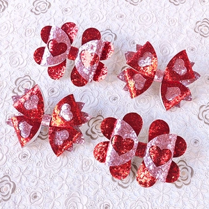 Détail de quatre barrettes nœuds pailletées en forme de cœur pour filles en rouge