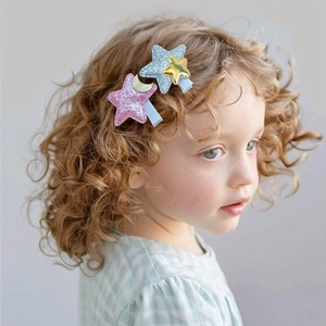 Close-up of cute glitter star hair clips with gold moon and star accents on a young girl