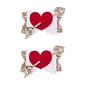 Dettaglio di fermagli per capelli di San Valentino con cuore rosso e freccia di paillettes