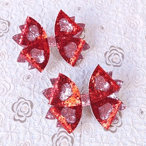 Détail de deux nœuds à cheveux rouges pailletés avec cœurs roses sur dentelle