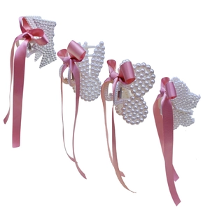 Detailed macro view of animal-shaped pearl hair claws with long pink satin ribbon streamers