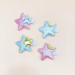 Detail of four glitter star hair clips for girls with moon and star metallic accents