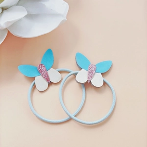 Dettaglio di due elastici per capelli a farfalla in pelle blu e bianca con glitter rosa