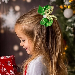 Detail of Christmas bow hair clip with gold antlers and snowflakes on a little girl