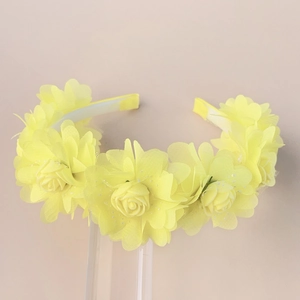 Macro detail of bright yellow floral headband with glittery petals on display stand