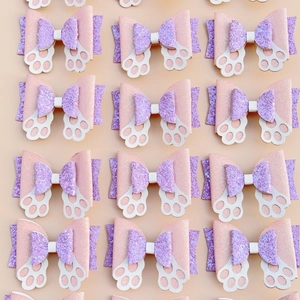 Close-up of pink and purple glitter bunny ear hair clips with white cat paw cutouts