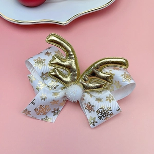 Detail of Christmas reindeer antler hair clip with white snowflake ribbon and plush ball