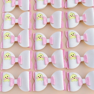 Detail of glitter pink and white leather hair bows with yellow chick cartoon accents