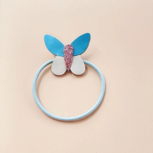 Dettaglio dell'elastico per capelli a farfalla in pelle PU con ali blu grigio e glitter rosa