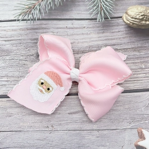 Detail of pink bow hair clip with embroidered Santa Claus and festive decorations