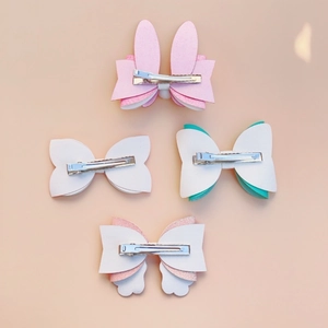 Detailed view of silver metal alligator clips on glitter bunny ear and bow hair accessories