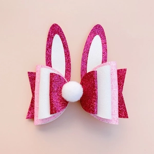 Detailed close-up of glitter Easter bunny ear hair clip with white plush pompom and bow
