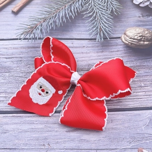 Close-up of red grosgrain ribbon bow hair clip with Santa Claus embroidery and white trim