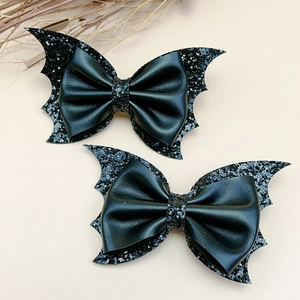 Close-up of black sequined bat wing hair clips with leather bows for Halloween parties
