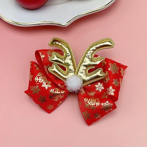Close-up of red Christmas bow hair clip with gold reindeer antlers and snowflake pattern